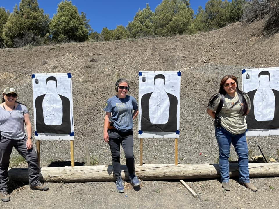 Three students in front of their silhouette targets after a women's class