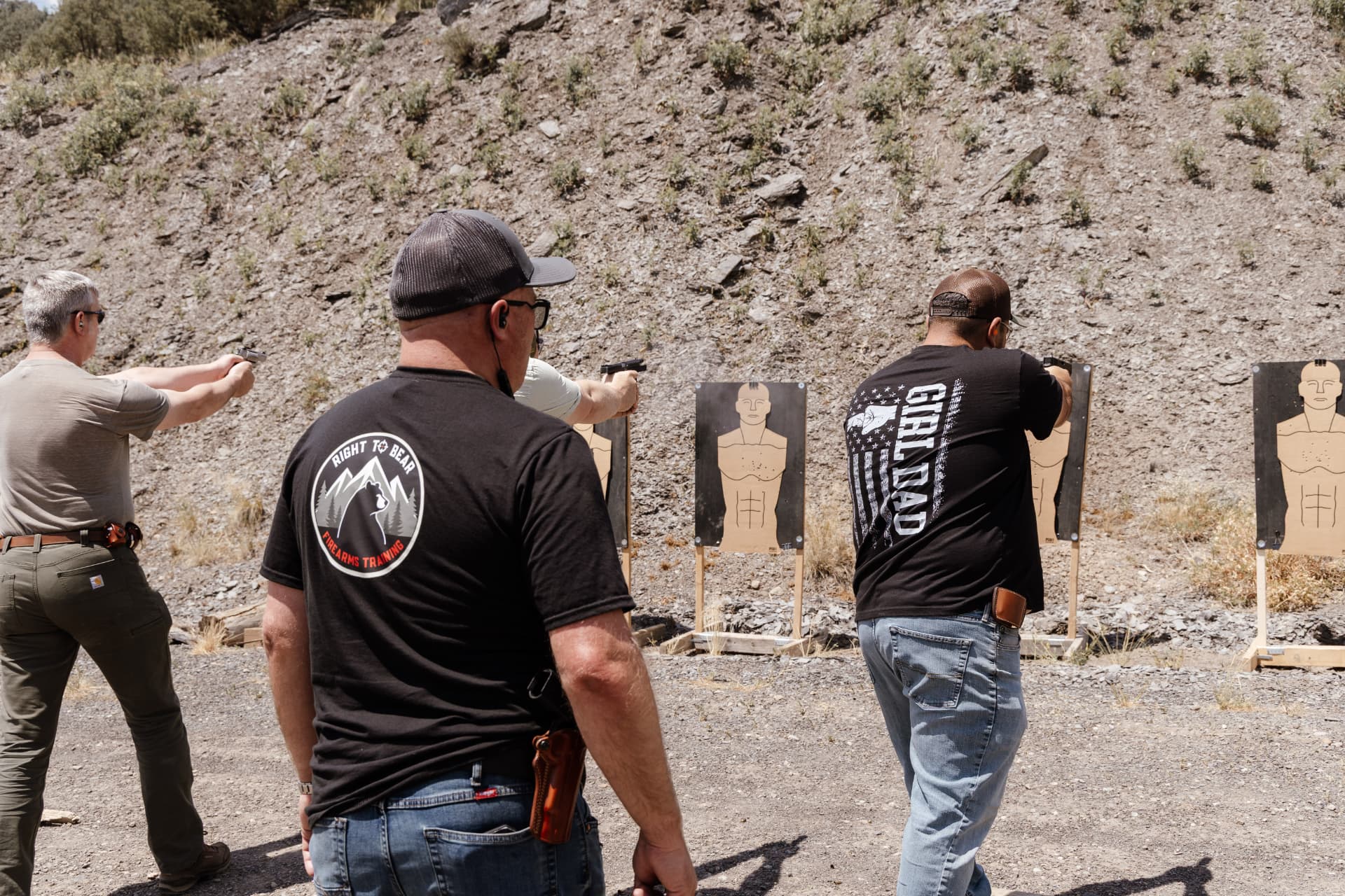 Three students shooting at silhouette targets side by side