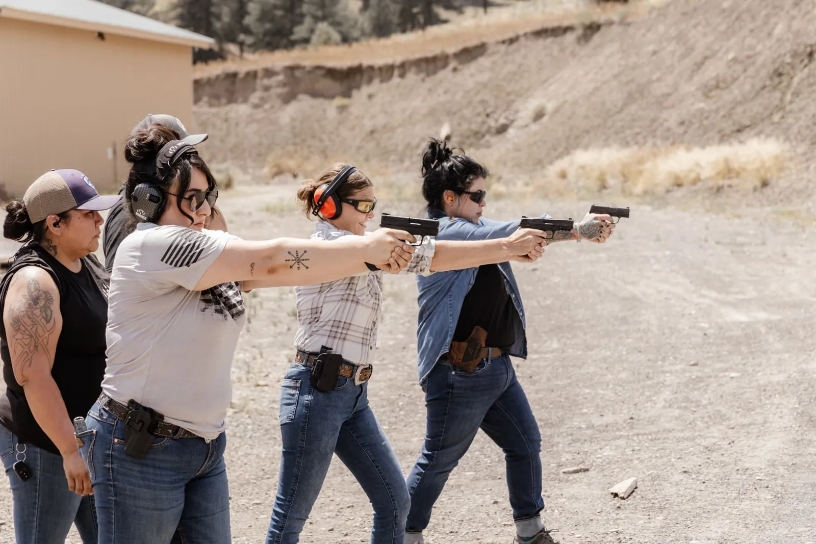 Four women shooting side by side on the line during a class