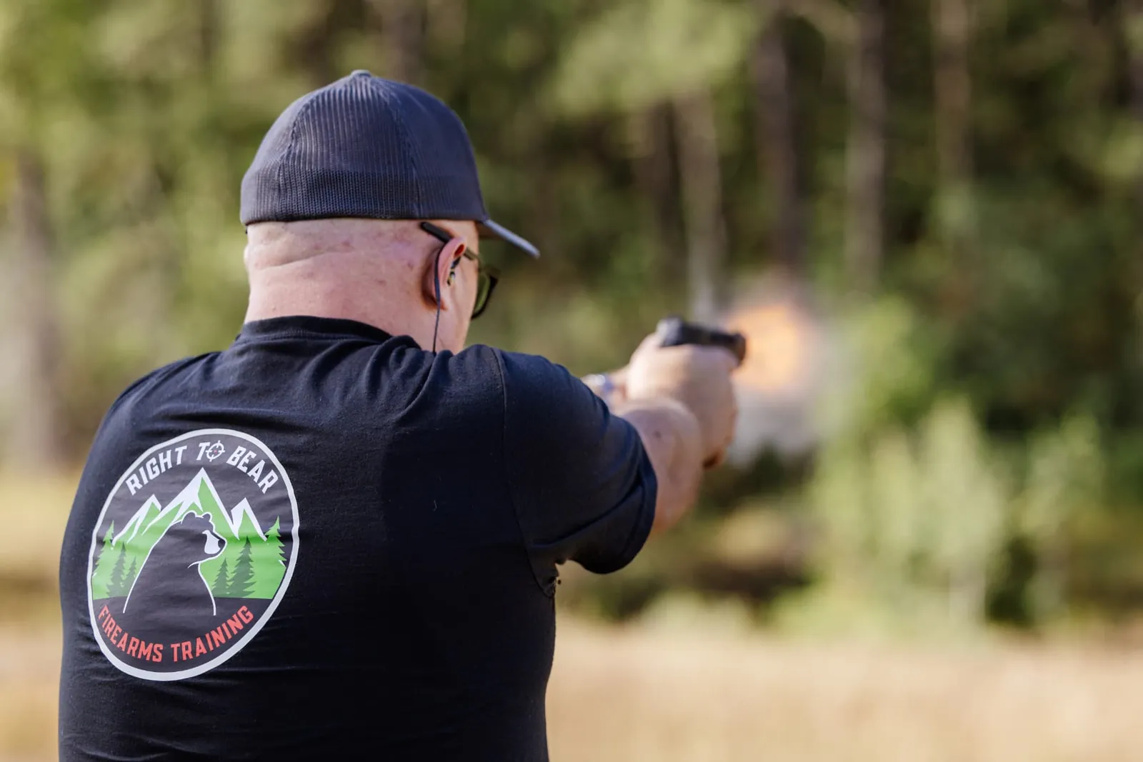 Shooter in a Right to Bear tee firing, muzzle flash visible